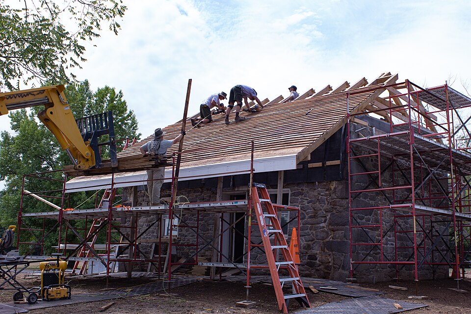 A roofing crew working on a roof deck from scaffolding